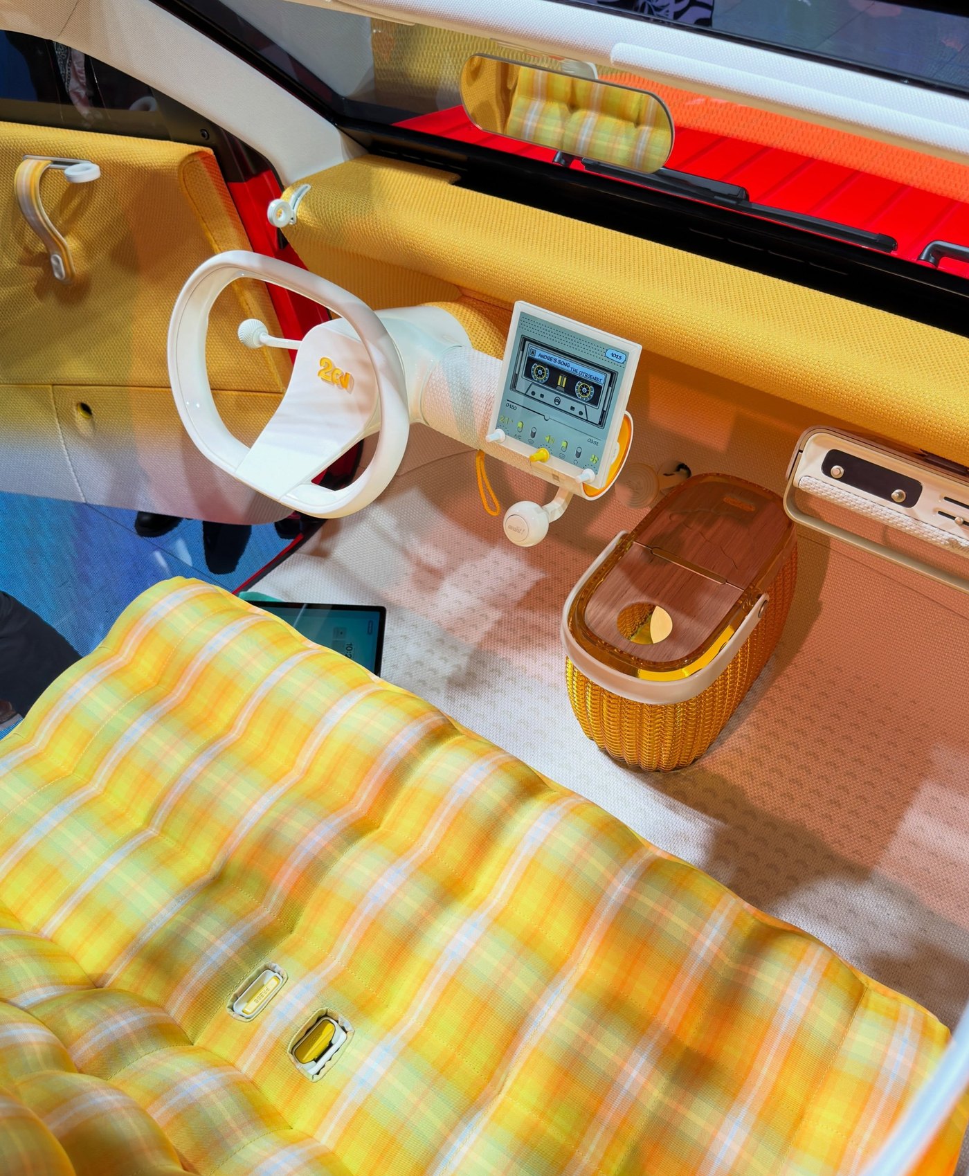 Inside: a single fabric bench, a one-spoke wheel and the instrument binnacle both carried on the steering column, an eight-inch square screen, and a removable basket where a centre console would normally sit. The detachable speaker unit sits on the shelf to the right.