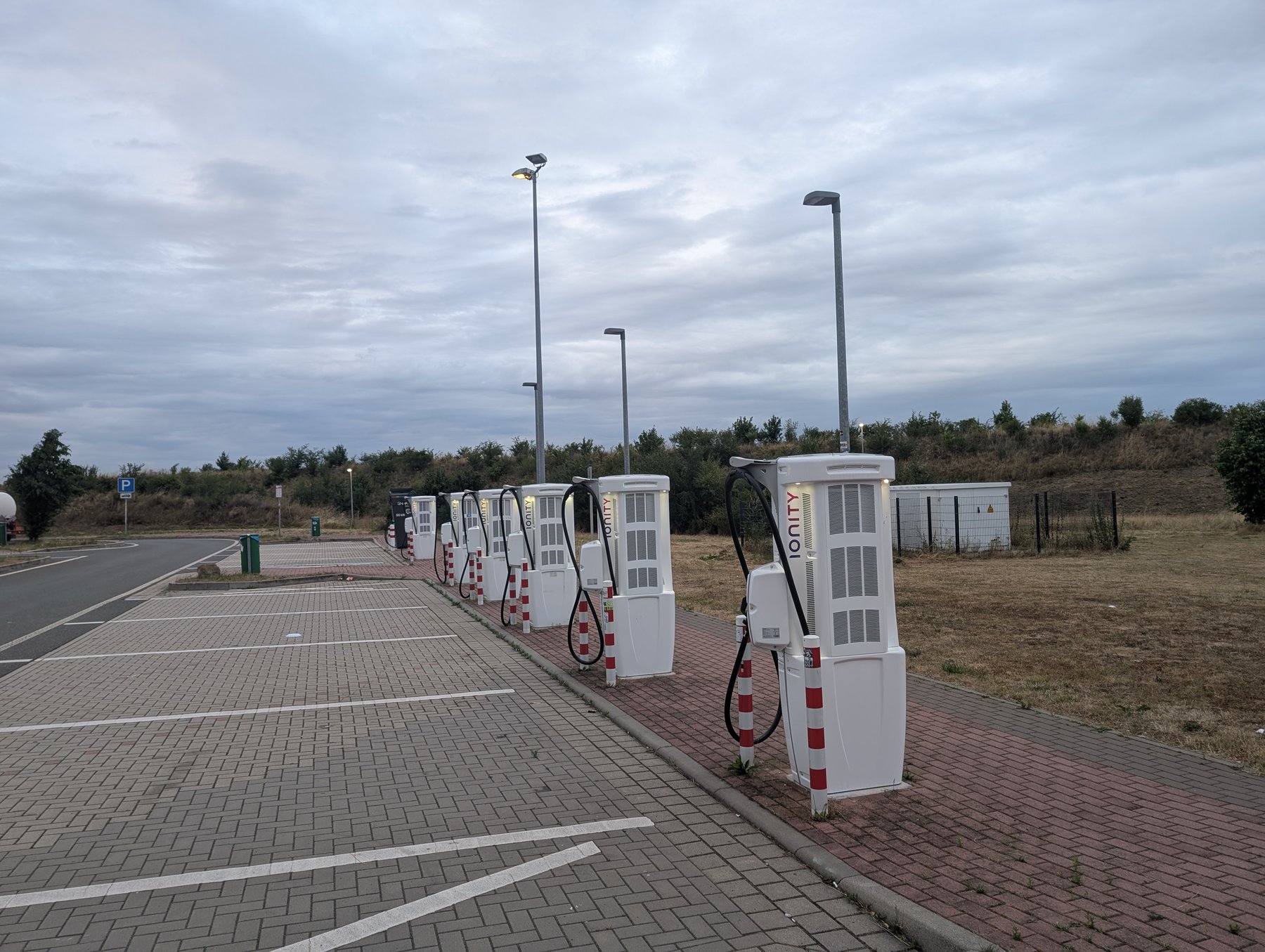 A row of Ionity high-power DC chargers at the Altenburger Land Nord service area in Germany. Hardware like this — wide-voltage, liquid-cooled cable, several hundred kilowatts — is still the exception on most charging networks, not the rule.