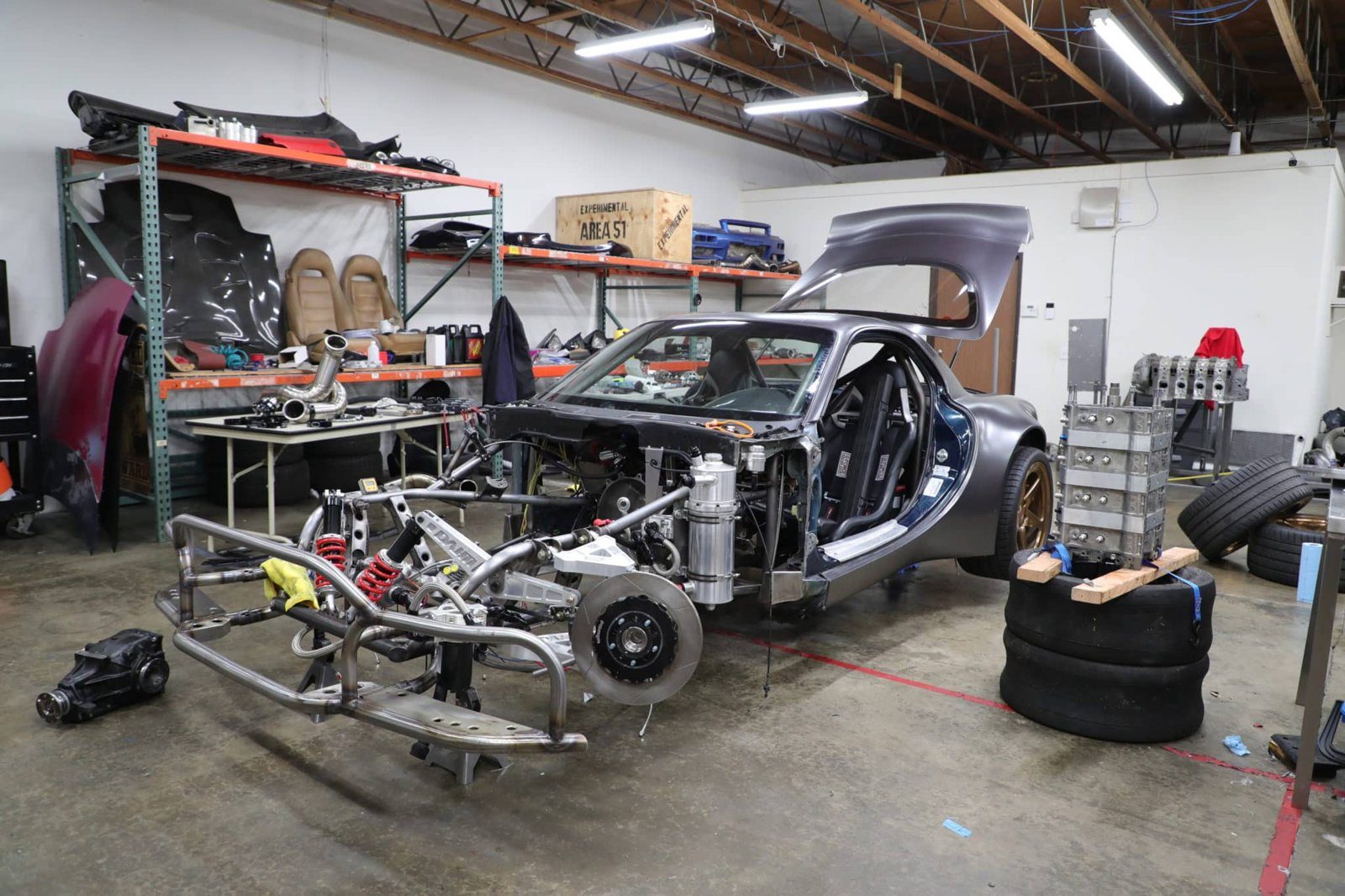 The RX-7's shell stripped to a bare chassis, with the custom AWD front subframe and suspension pulled out for fitment.